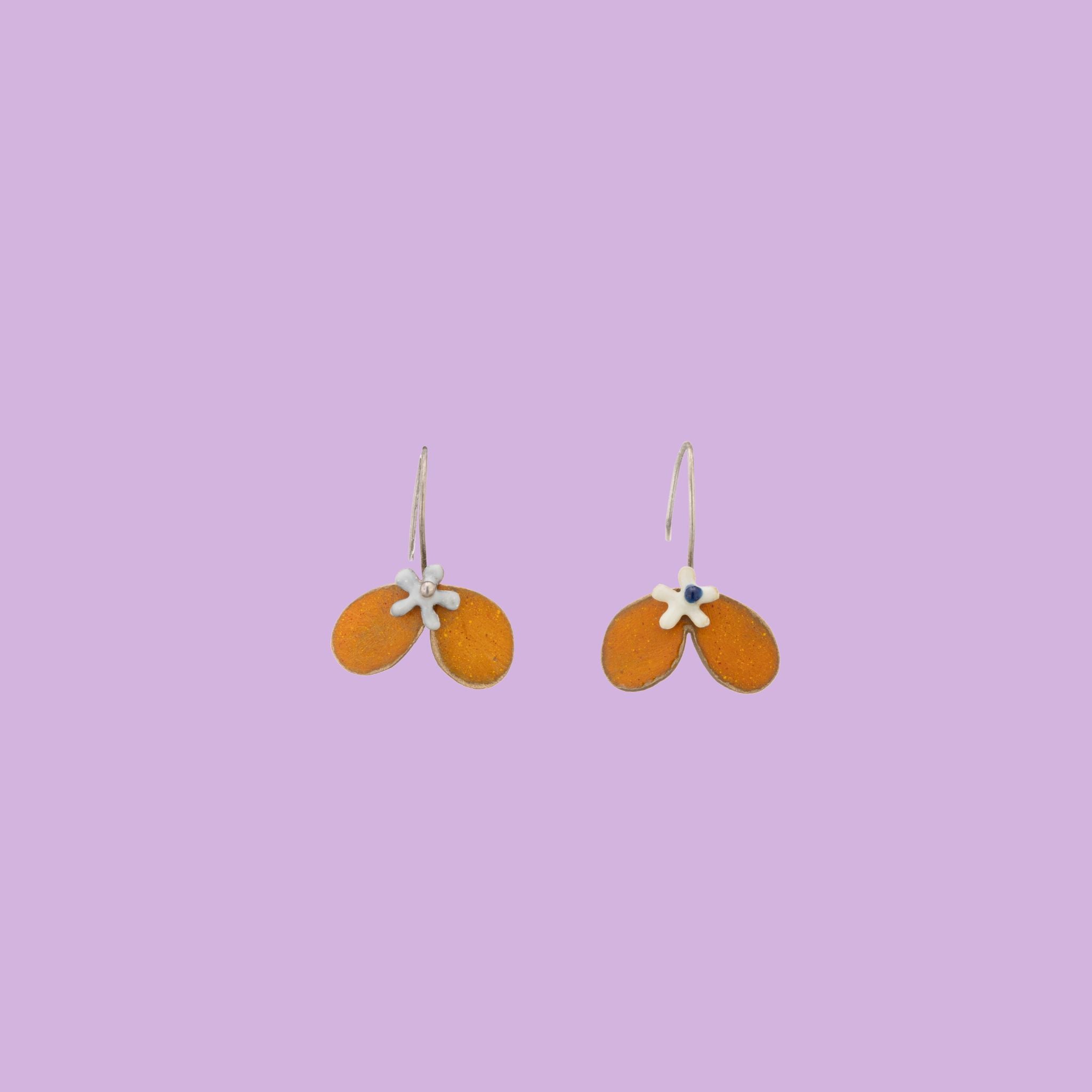 Handmade by Fabian Crosta, these orange petal-shaped brass earrings add a vibrant and elegant touch to any outfit.