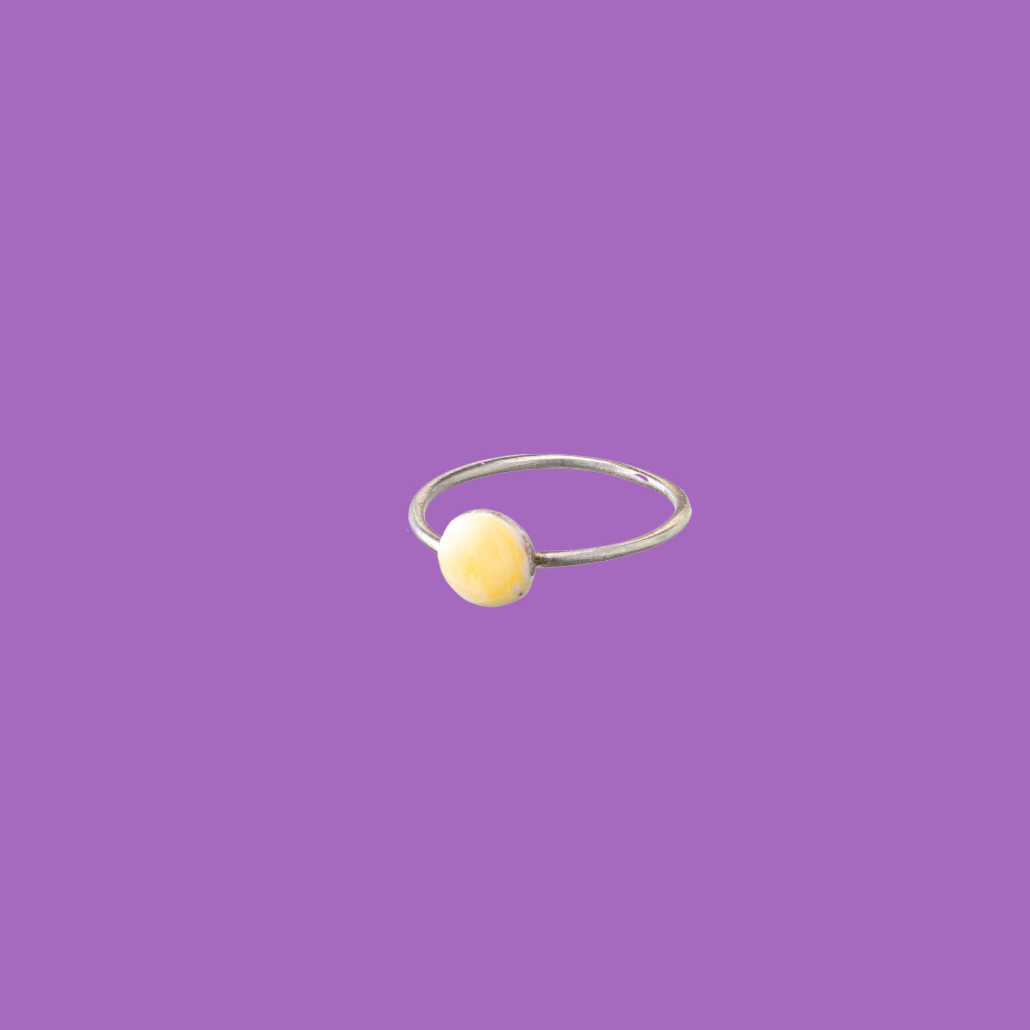 Questo anello in ottone presenta un accento circolare smaltato giallo scuro di medie dimensioni.