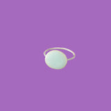 Anello in ottone con un grande elemento circolare smaltato verde chiaro.