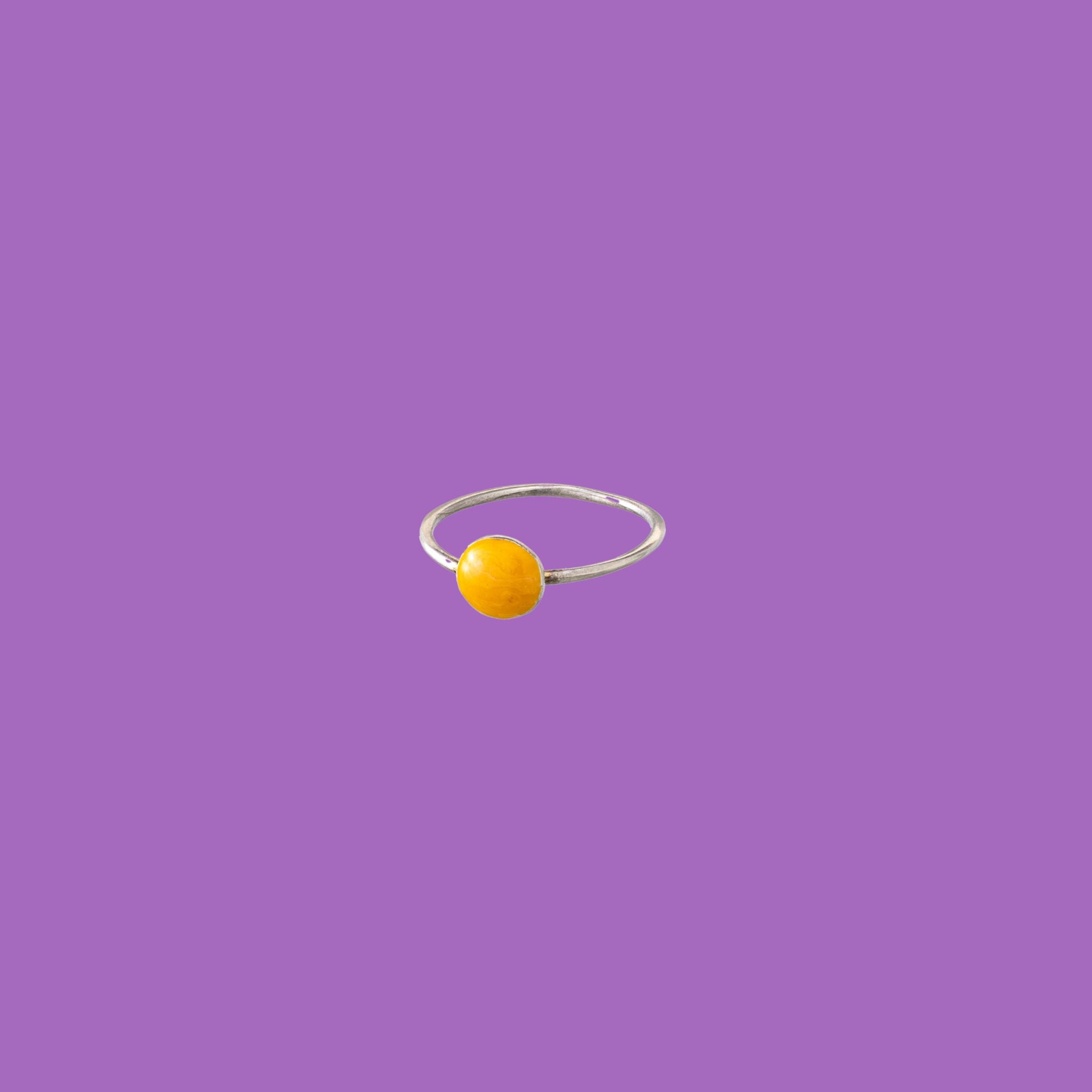 Questo anello in ottone presenta un accento circolare smaltato arancione chiaro di medie dimensioni.