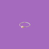 Questo anello in ottone presenta un piccolo elemento circolare smaltato rosa.