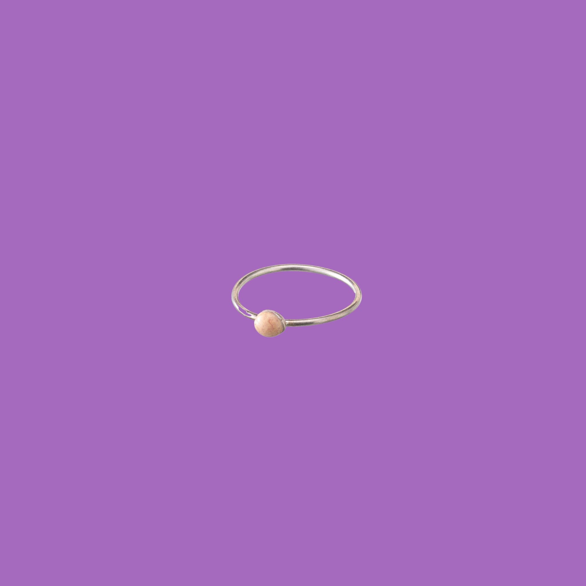 Questo anello in ottone presenta un piccolo accento circolare smaltato rosa.