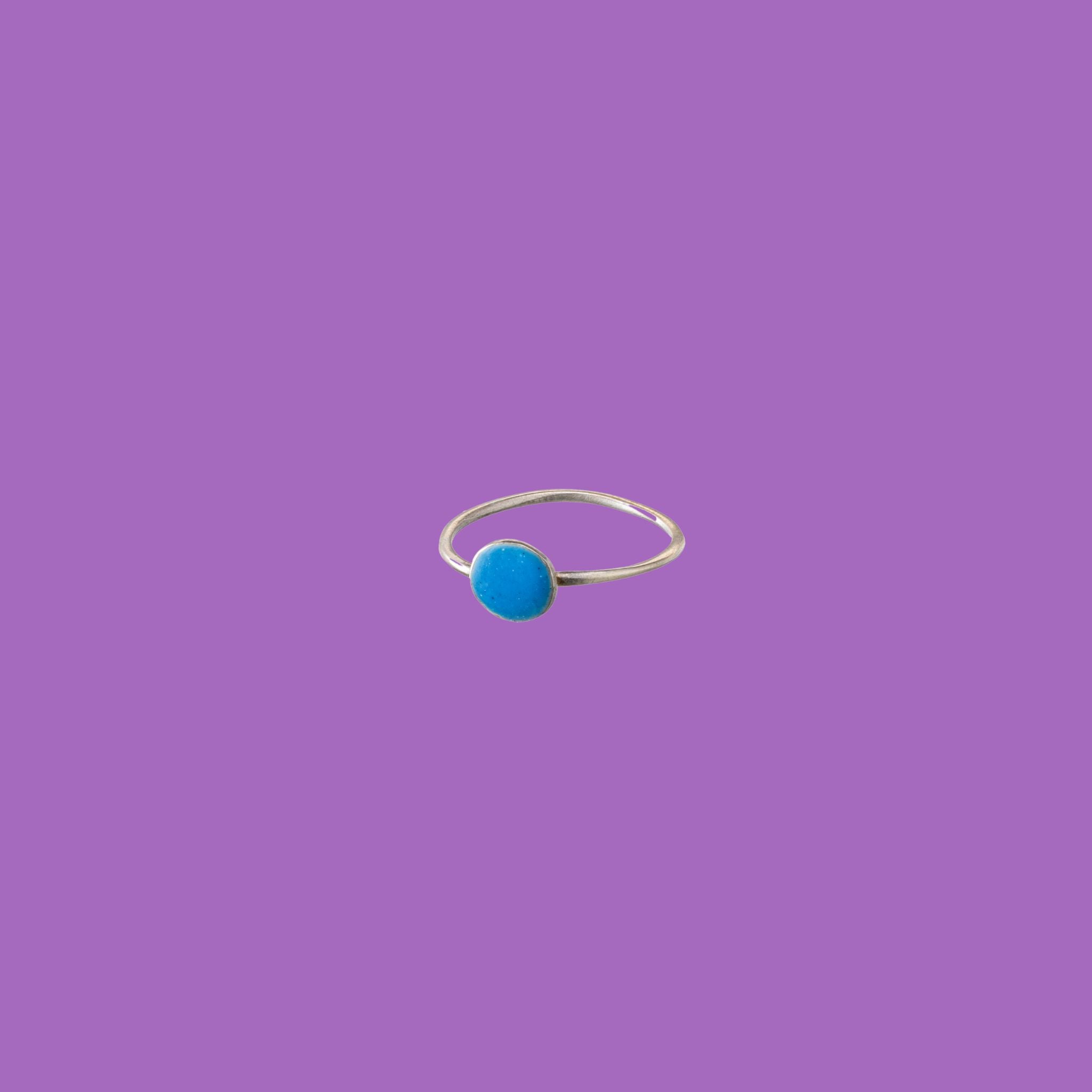 Questo anello in ottone presenta un accento circolare smaltato blu di medie dimensioni.