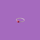 Questo anello in ottone presenta un piccolo elemento circolare smaltato rosso.