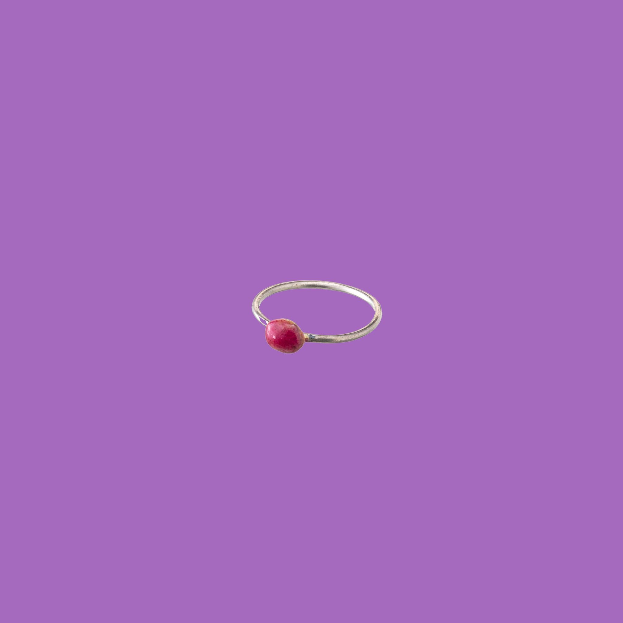 Questo anello in ottone presenta un piccolo elemento circolare smaltato rosso.